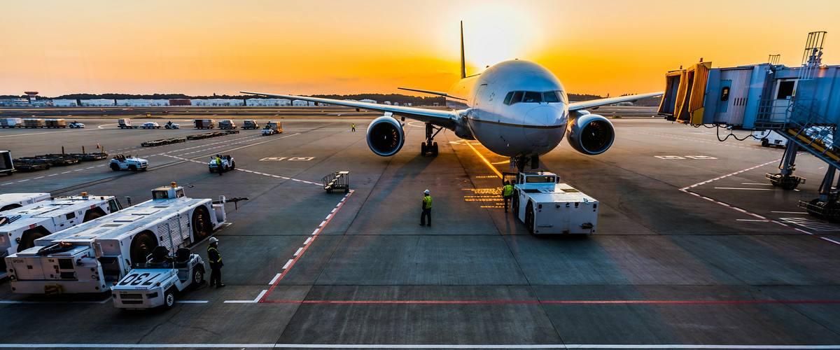 Passenger and cargo aircraft on the apron at sunset with ground crews